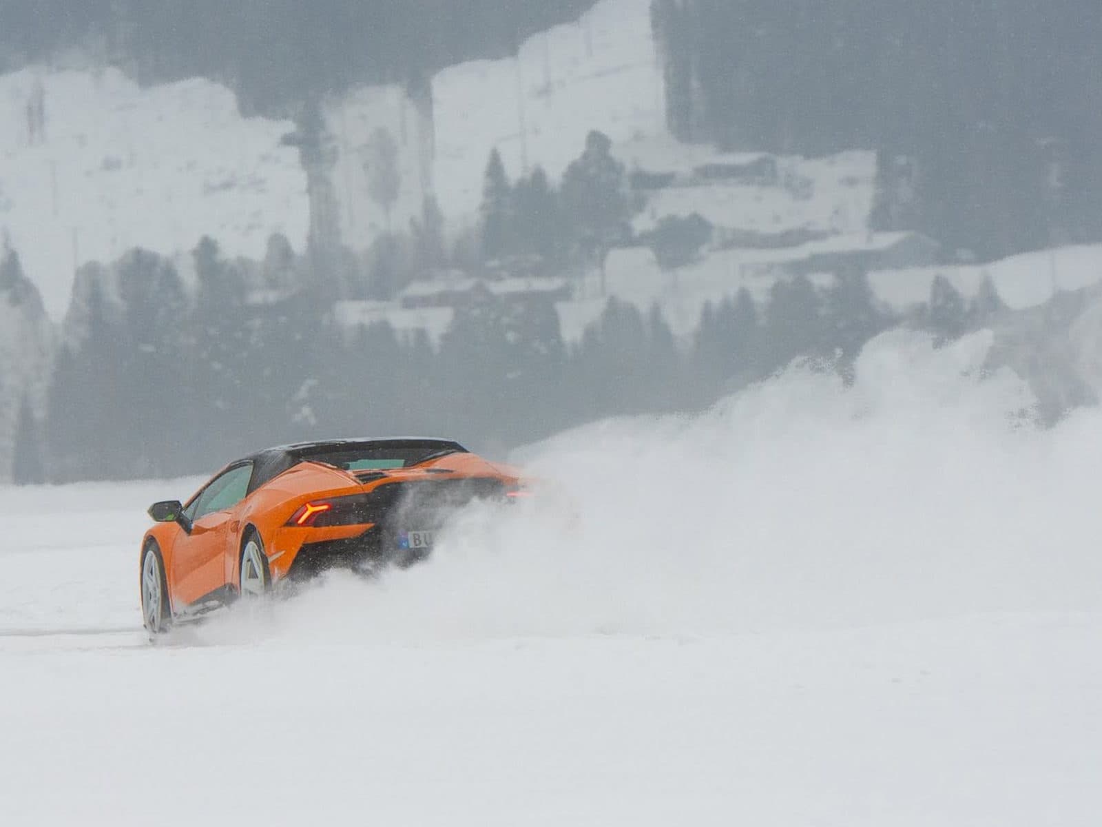 Oransje supersportsbil i drift på isbanen